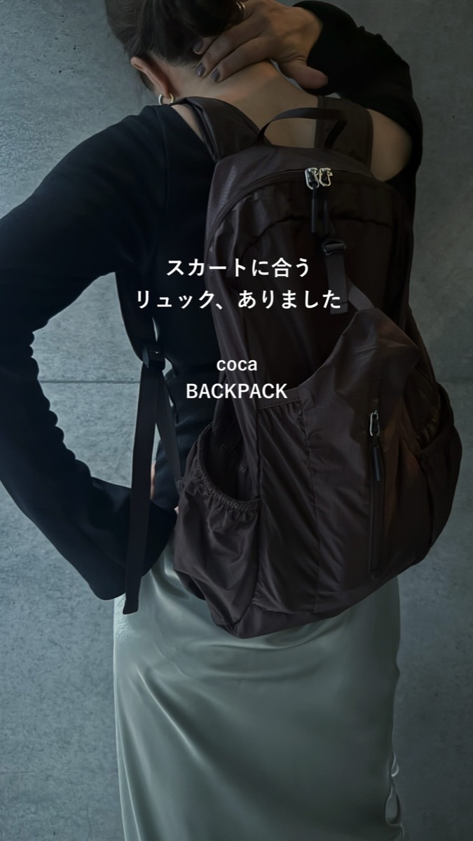 黒のリブトップスにミントのサテンロングスカート、ブラウンのcocaのリュックを背負った後ろ姿