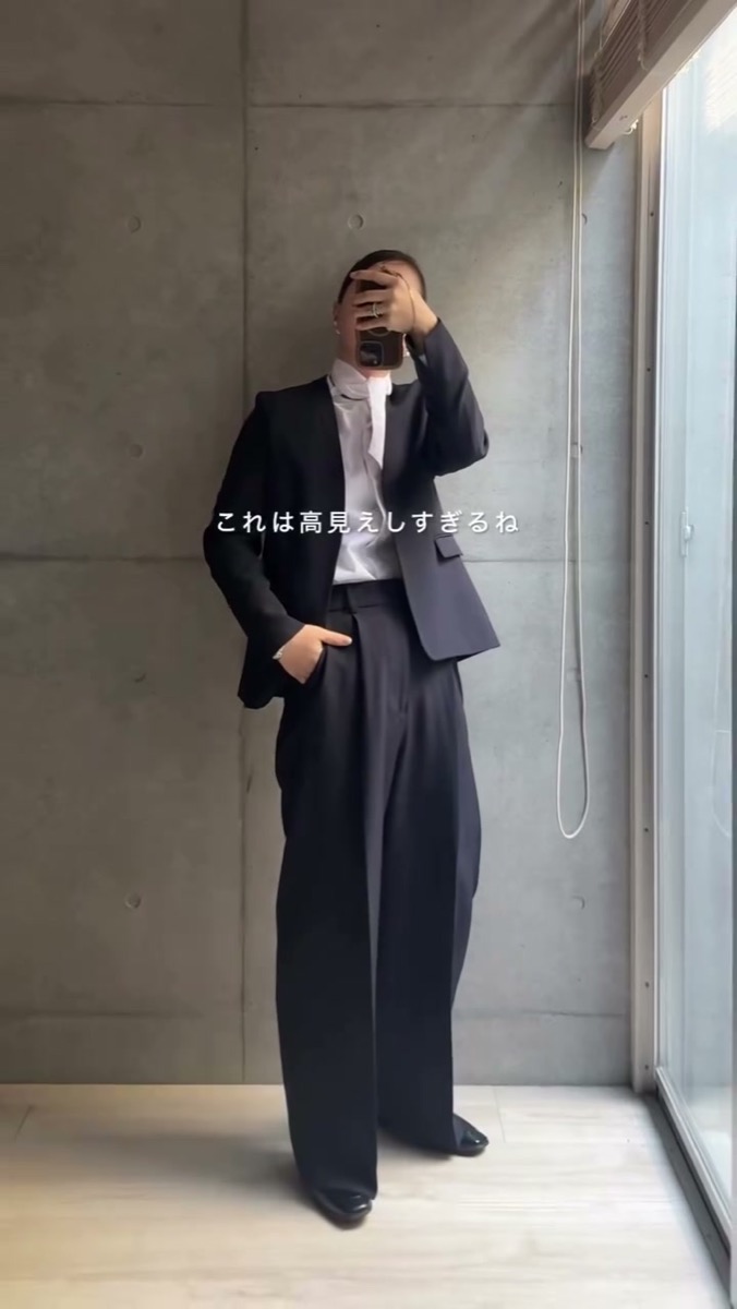 ノーカラースーツのセットアップを着た全身。深みのあるネイビーのジャケットとワイドパンツ
