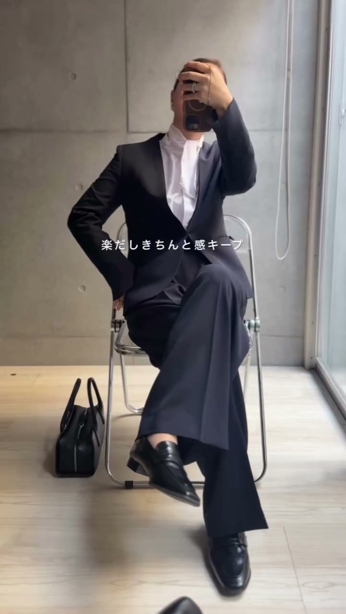 ノーカラースーツで椅子に座った様子。座ってもシルエットが崩れない
