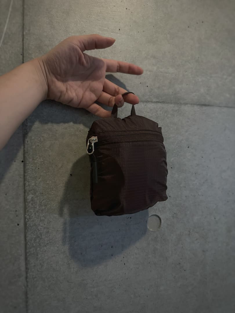 cocaのポケッタブルバックパックを畳んで小さくしたところを手に持っている