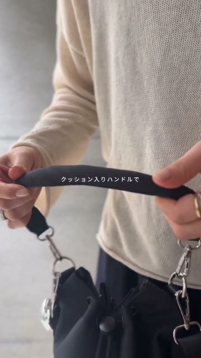 グリーンレーベルのはっ水ドロストバッグのクッション入りハンドルを両手で持って、丸みを見せているところ