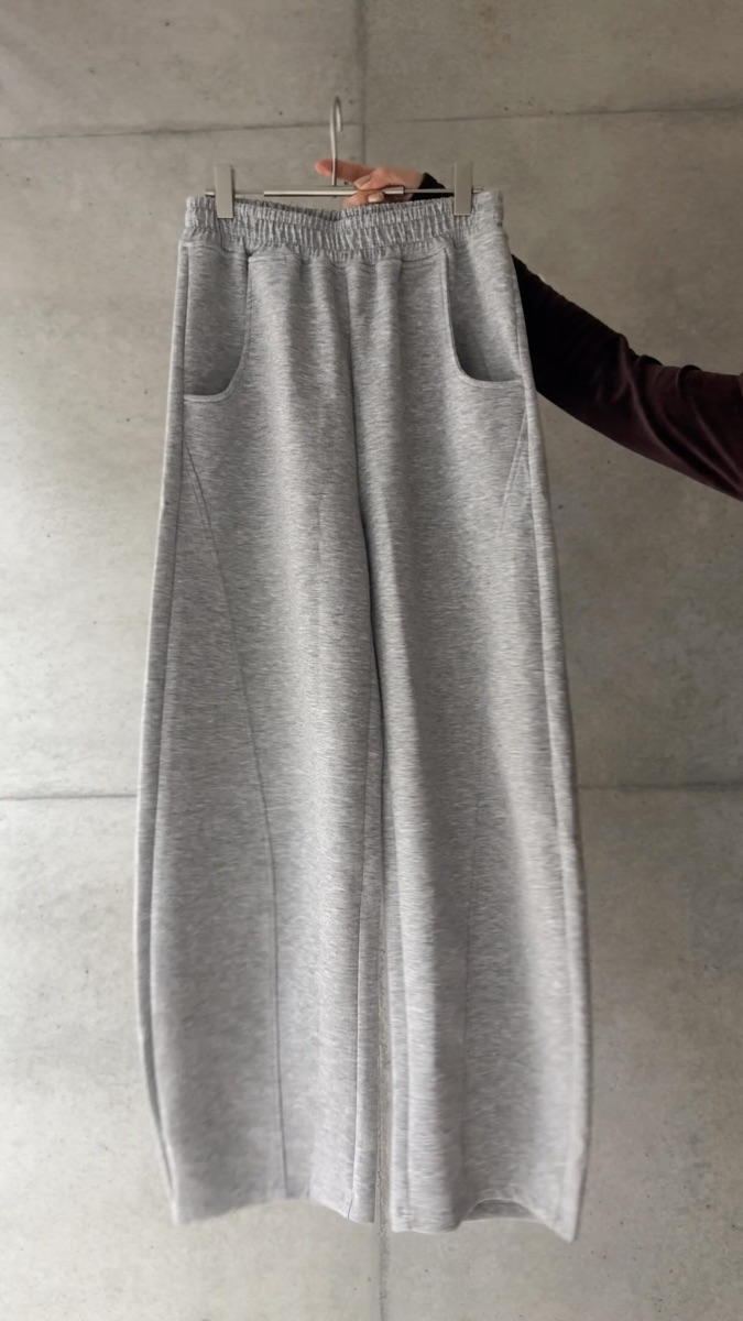 ハンガーに掛けたグレーのカーブパンツ。ウエストはゴムで、脚に沿ってカーブする切り替え線が入っている